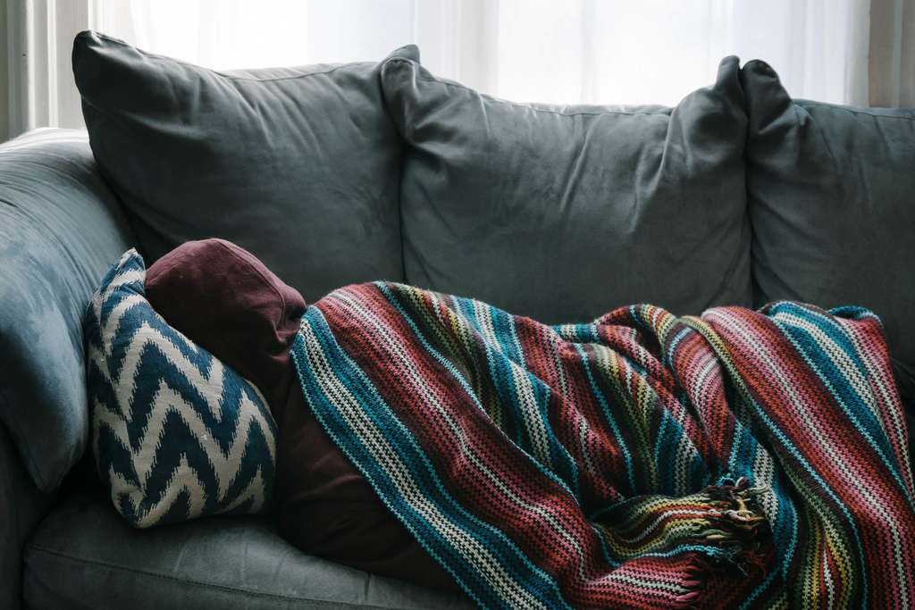 sick person laying down on couch