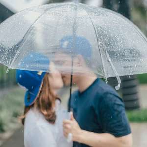 couple kissing in rain under umbrella