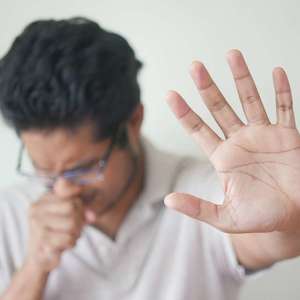 man coughing with hand up