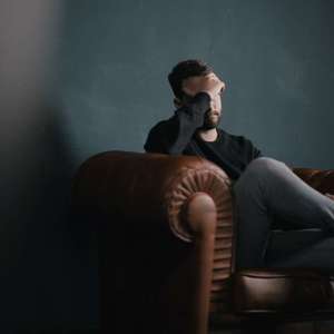 Man sitting in chair with head in hands