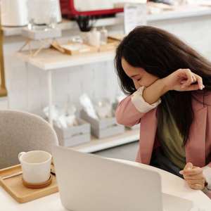 woman sneezing into arm