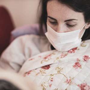 woman wearing mask laying down sick