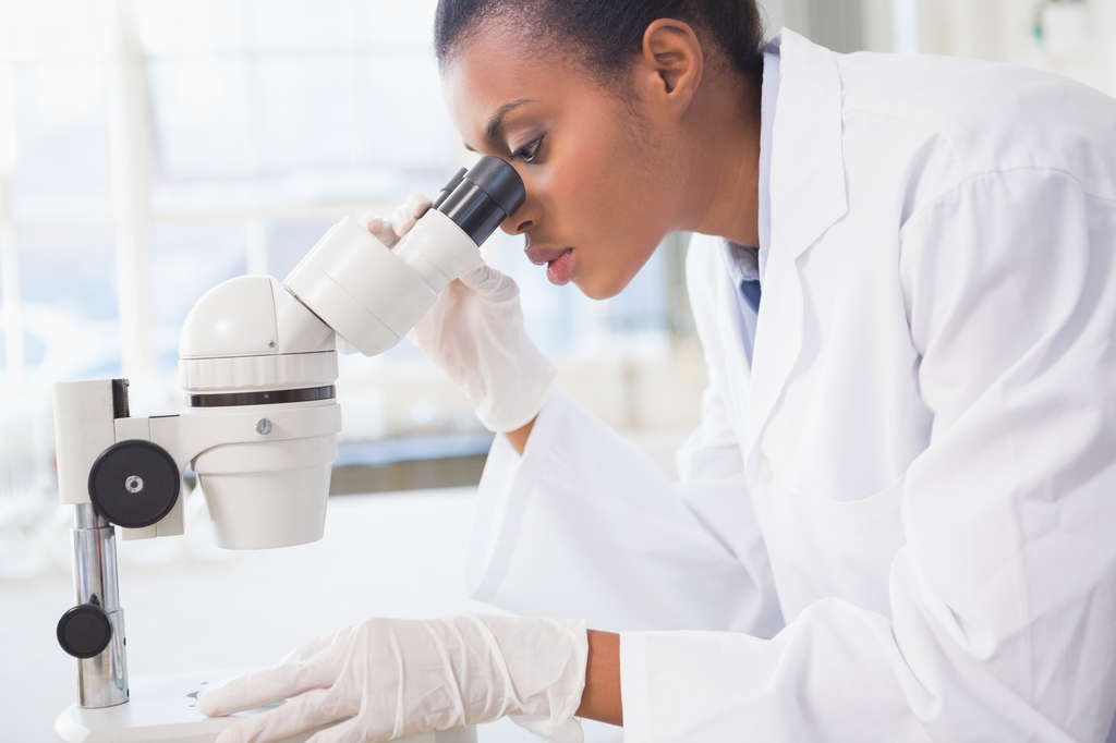 Woman lab tech looking into microscope
