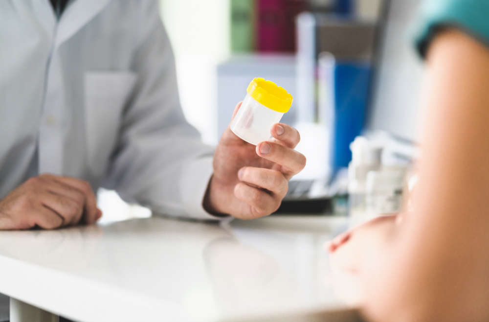 lab tech giving specimen cup to employee for drug testing