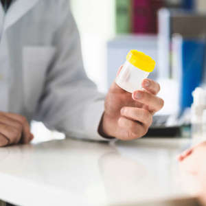 lab tech giving specimen cup to employee for drug testing