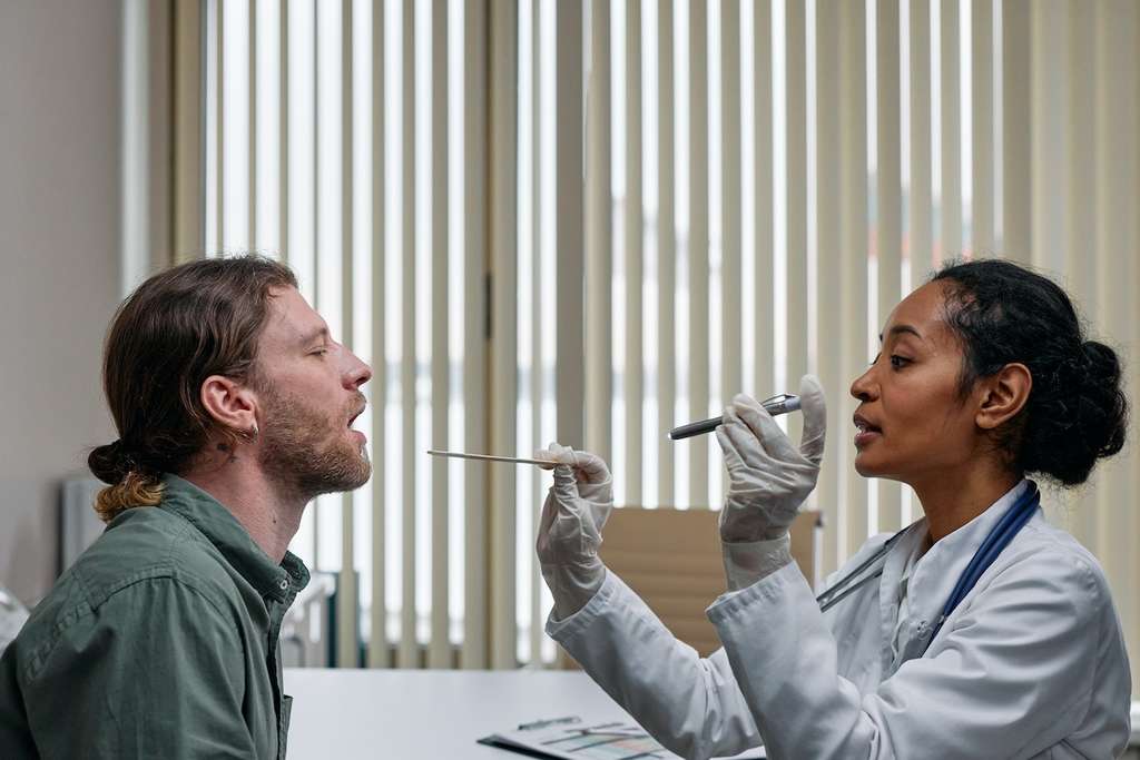 Doctor looking into patient’s mouth with a flashlight