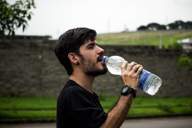 Man drinking from plastic water bottle
