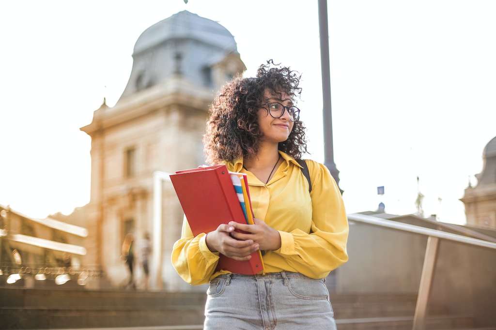 College student standing outside holding textbook
