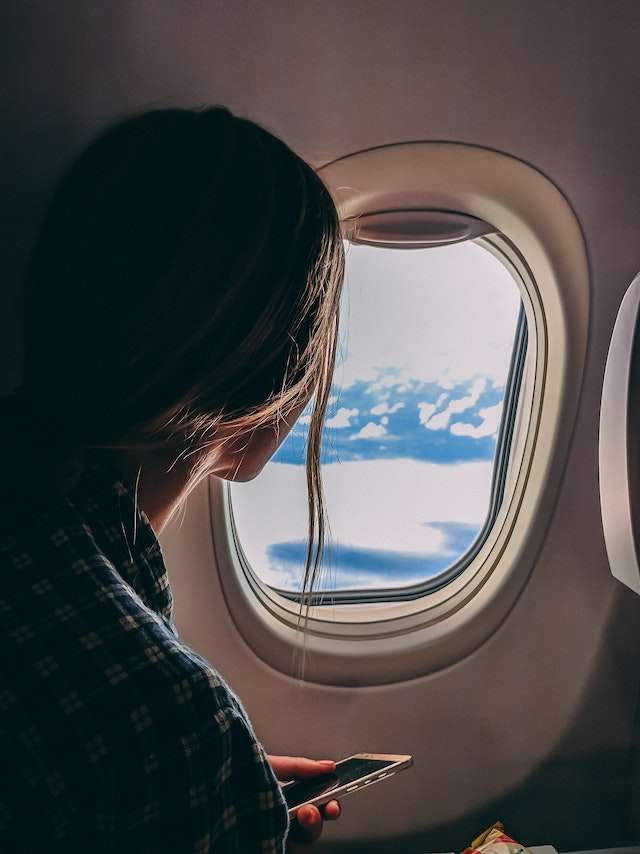 Woman sitting in window seat looking out airplane window
